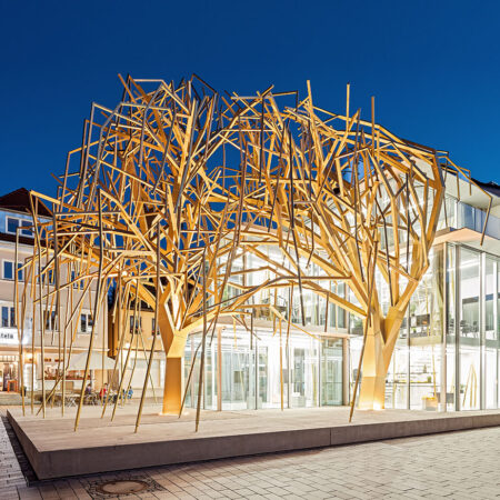 Ein von goldenen Stahlweiden überwölbter Pavillon auf einem Marktplatz.