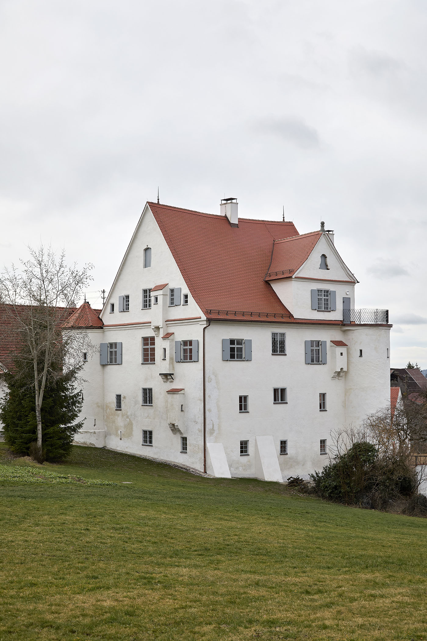 Schloss mit weißen Wänden, rotem Ziegeldach, Erkern und Vorsprüngen